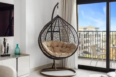 a hanging chair in a living room with a balcony at Stylish 1BR with Balcony and Burj AlArab View in Dubai