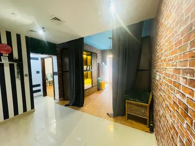 a living room with a brick wall and a room with curtains at Affordable Hostel in Al Barsha 1 Near Mall of Emirates Metro in Dubai
