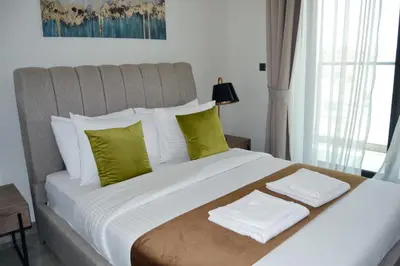 a bedroom with a large white bed with green pillows at Cozy spacious Modern 1 bedroom Apartment in Dubai