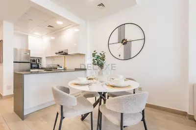 a dining room with a table and chairs and a clock on the wall at Stay Near the Park with Easy Exit from JVC, Just Minutes to Dubai Marina and Palm Jumeirah - Bloom Towers A, JVC by Deluxe Holiday Homes in Dubai