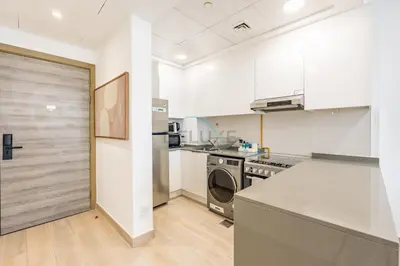 a kitchen with a washer and dryer next to a door at Stay Near the Park with Easy Exit from JVC, Just Minutes to Dubai Marina and Palm Jumeirah - Bloom Towers A, JVC by Deluxe Holiday Homes in Dubai