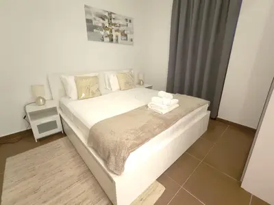 a bedroom with a large white bed with towels on it at Bright & Spacious 2BR in JVT Community in Dubai