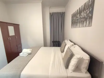 a bedroom with a bed with white sheets and pillows at Bright & Spacious 2BR in JVT Community in Dubai