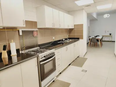 a kitchen with white cabinets and a stove top oven at Bright & Spacious 2BR in JVT Community in Dubai