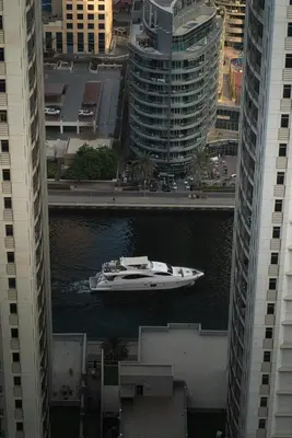 a boat in the water between two tall buildings at Elegant 2-Bedroom Apartment with Breathtaking Cityscape in Dubai