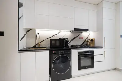 a kitchen with white cabinets and a washer at PNB Living - Luxury Studio with Canal Views - Trillionaire Residences, Business Bay in Dubai