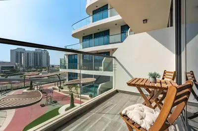 a balcony with two chairs and a table on a building at Walking distance to Dubai Miracle Garden and Butterfly Garden, Few minutes drive to Mall of the Emirates and IMG Worlds of Adventure - Samana Park Views, Arjan by Deluxe Holiday Homes in Dubai