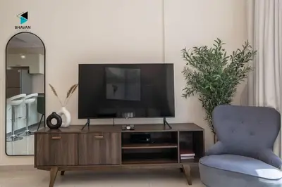 a living room with a tv and a blue chair at Stylish Stay at Bay Central with Skyline Views in Dubai