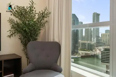 a chair in front of a window with a view of a city at Stylish Stay at Bay Central with Skyline Views in Dubai