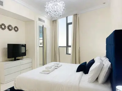 a white bedroom with a large bed and a tv at 2 Bedroom Apt in Damac Capital Bay Tower A, Business Bay by Luxaura in Dubai