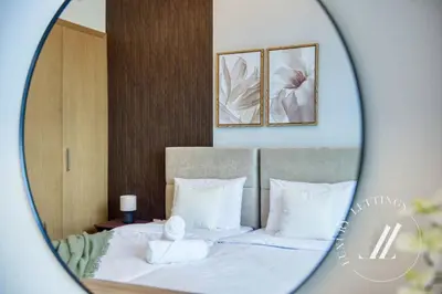 a mirror reflecting a bed with white sheets and pillows at Luxury 1BR Harbour Views Tower 2 Creek Harbour Dubai in Dubai