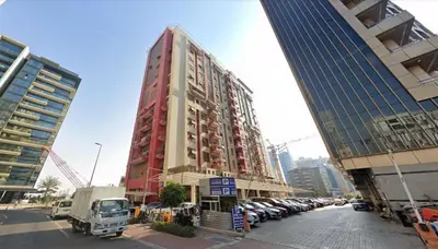 a tall red building with cars parked in a parking lot at Green Heaven Partition Room in Green View 3 in Dubai