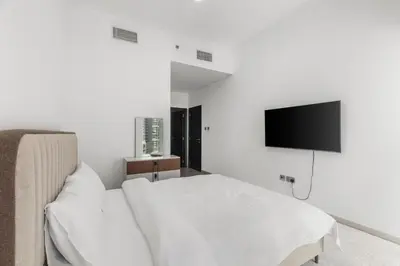 a white bedroom with a bed and a flat screen tv at 2BR In The World-Famous Twisted Skyscraper in Dubai