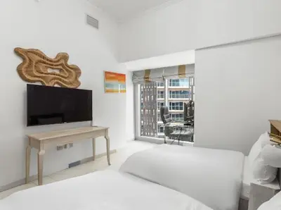 a white living room with a television and a table at 2BR In The World-Famous Twisted Skyscraper in Dubai