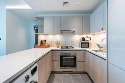 a large kitchen with white counters and appliances at High-Floor 2BR with Skyline Views, Steps from a Park, Minutes Drive to Meydan Golf Club and Ras Al Khor Wildlife Sanctuary, Sobha Hartland The Crest Tower C, Sobha Hartland by Deluxe Holiday Homes in Dubai