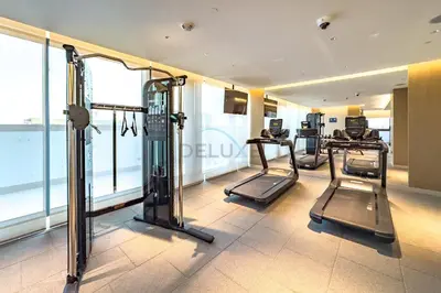a gym with several tread machines in a room with windows at High-Floor 2BR with Skyline Views, Steps from a Park, Minutes Drive to Meydan Golf Club and Ras Al Khor Wildlife Sanctuary, Sobha Hartland The Crest Tower C, Sobha Hartland by Deluxe Holiday Homes in Dubai