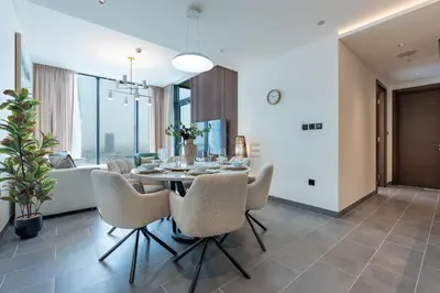 a dining room and living room with a table and chairs at High-Floor 2BR with Skyline Views, Steps from a Park, Minutes Drive to Meydan Golf Club and Ras Al Khor Wildlife Sanctuary, Sobha Hartland The Crest Tower C, Sobha Hartland by Deluxe Holiday Homes in Dubai
