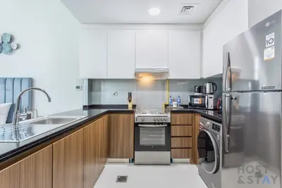 a kitchen with a stainless steel refrigerator and a dishwasher at Cozy Studio in Orchid - Damac Hills Dubai in Dubai