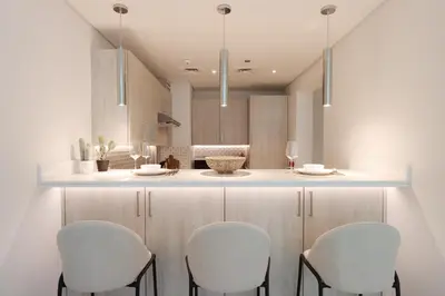 a kitchen with white chairs and a counter top at Beachfront 1BR Seven Palm Rooftop Pool & Views in Dubai
