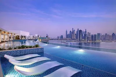 a hotel swimming pool with a view of a city at Beachfront 1BR Seven Palm Rooftop Pool & Views in Dubai
