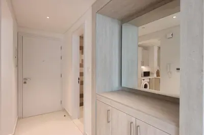 a white kitchen with a mirror and a door at Beachfront 1BR Seven Palm Rooftop Pool & Views in Dubai