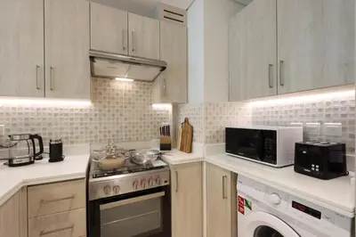 a kitchen with a stove and a microwave at Beachfront 1BR Seven Palm Rooftop Pool & Views in Dubai
