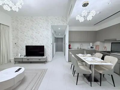 a kitchen and living room with a table and chairs at Skyline Escape 2BR with Balcony Pool & Gym in Dubai