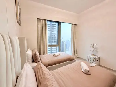 a bedroom with two beds and a large window at Skyline Escape 2BR with Balcony Pool & Gym in Dubai