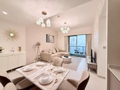 a living room with a table and chairs and a couch at Skyline Escape 2BR with Balcony Pool & Gym in Dubai