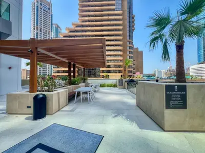 a patio with a table and chairs and a large building at Modern Waterfront Living with Stunning Views in Dubai