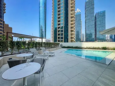 a rooftop patio with tables and chairs and a pool at Stylish Coastal Living with Premium Amenities in Dubai