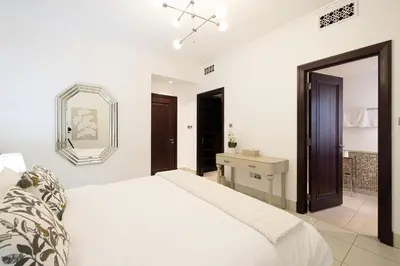 a white bedroom with a bed and a mirror at Elegant 1-BR in Downtown Dubai's Old Town in Dubai