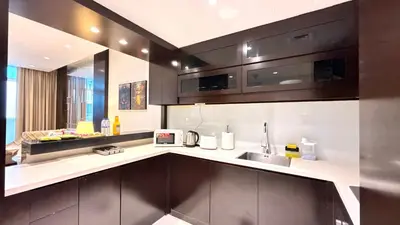 a kitchen with brown cabinets and a sink and a counter at LUX 1BR 5 Min Walk Dubai Mall - DAMAC Upper Crest in Dubai
