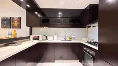 a kitchen with dark brown cabinets and a microwave at LUX 1BR 5 Min Walk Dubai Mall - DAMAC Upper Crest in Dubai