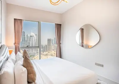 a white bedroom with a large window with a view at Grande Signature 2BR Burj Khalifa & Dubai Fountain in Dubai