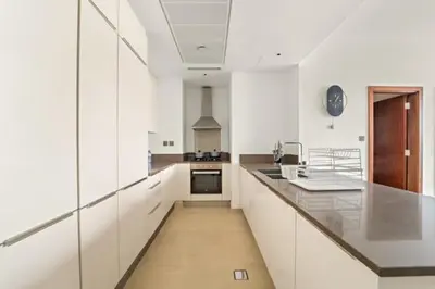 a large white kitchen with white cabinets and a counter at FIRST CLASS 1BR Breathtaking Marina Views in Dubai