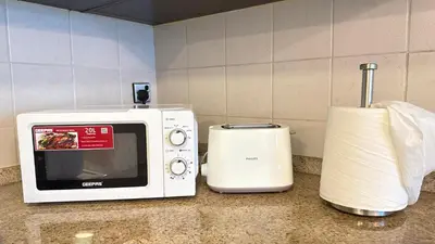 a white microwave sitting on a counter next to a toaster at Studio with Amazing Lake Views in Arch Tower, JLT in Dubai