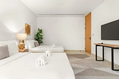 a white room with two beds and a flat screen tv at FIRST CLASS 3BR Comfort and Style , Business Bay in Dubai