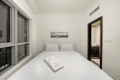 a white bed in a room with a window at FIRST CLASS 1BR Marina Skyline Escape in Dubai