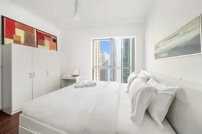 a white bedroom with a large white bed with white pillows at FIRST CLASS 1BR Marina Skyline Escape in Dubai