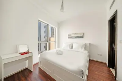 a white bedroom with a large white bed and windows at FIRST CLASS 1BR Marina Skyline Escape in Dubai