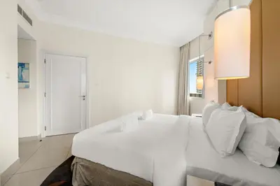 a white bedroom with a large bed with white pillows at FIRST CLASS 1BR Iconic Burj Khalifa View in Dubai