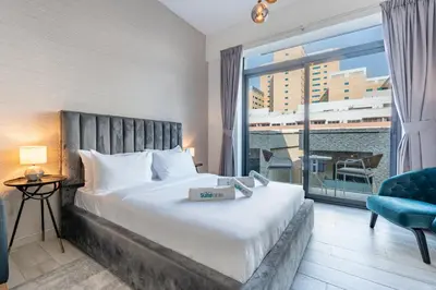 a hotel room with a bed and a large window at Chic Studio in Vibrant Oxford Residence in Dubai