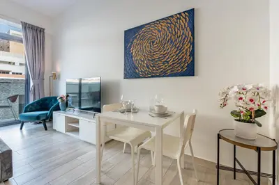 a dining room with a white table and chairs at Chic Studio in Vibrant Oxford Residence in Dubai