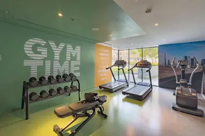 a gym with several tread machines in a room at Chic Studio in Vibrant Oxford Residence in Dubai