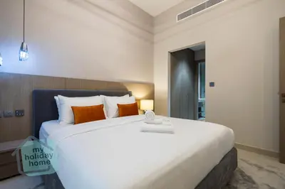 a bedroom with a large white bed with orange pillows at Modern 1BR in JVC Pool, Gym & Free Parking in Dubai