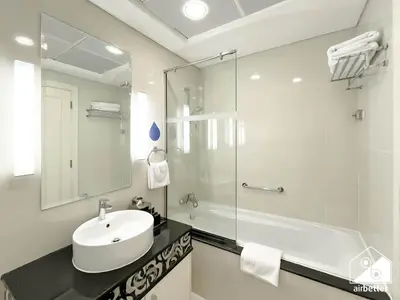 a white bathroom with a sink and a shower at Luxury Living Skyline Views l 2BR with Pool & Gym in Dubai