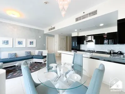 a kitchen and living room with a glass table and chairs at Luxury Living Skyline Views l 2BR with Pool & Gym in Dubai