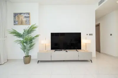 a living room with a large tv on a white wall at Modern & Luxurious 2BR Penthouse in MBR City District One Dubai in Dubai