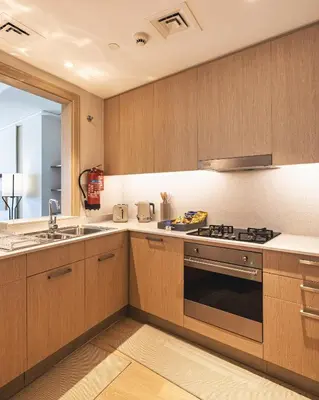 a kitchen with wooden cabinets and a sink and a stove at The Opera Grand Ultra Luxury Suite Burj Khalifa and Fountain View in Dubai